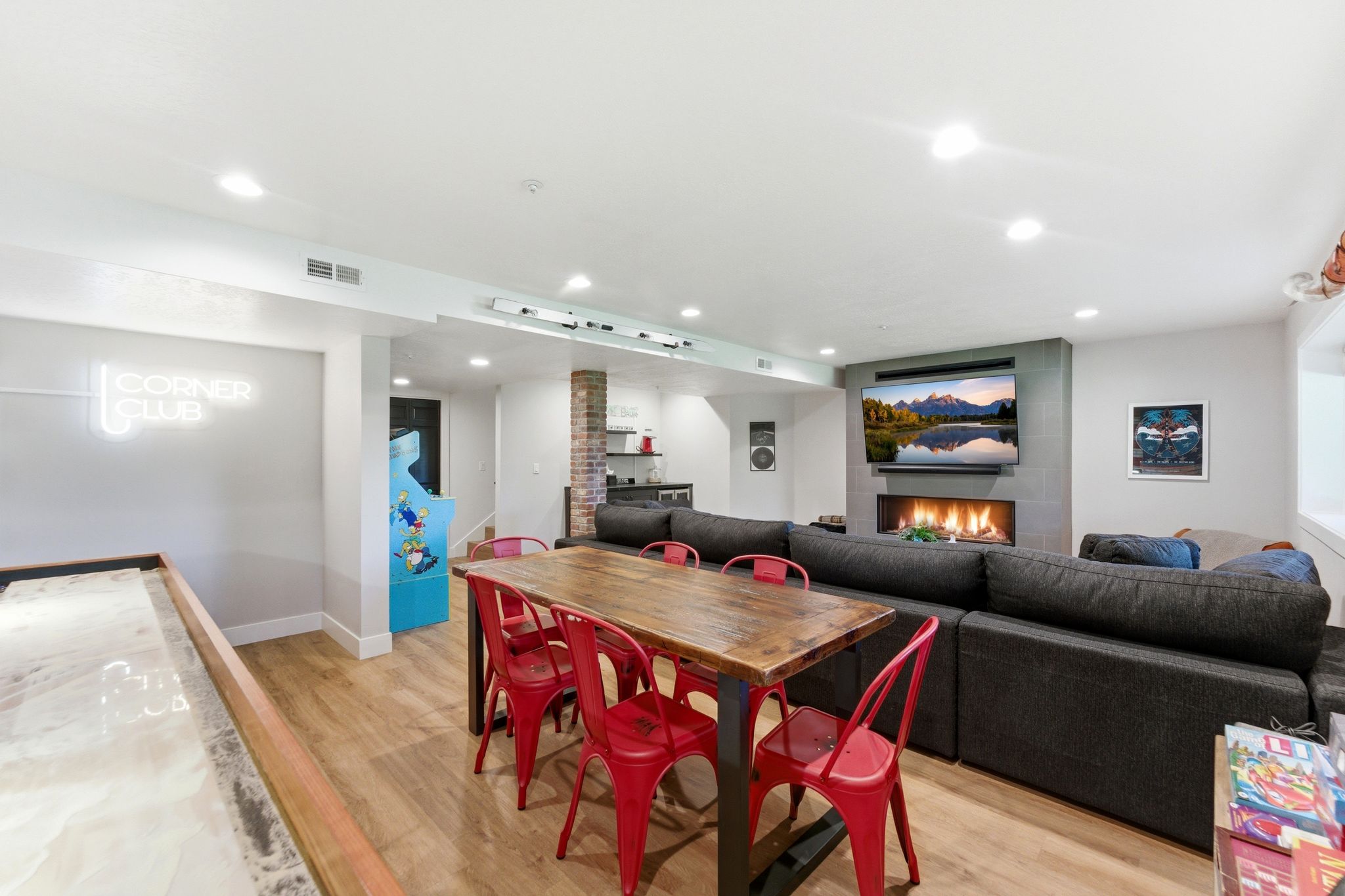 Entertainment area featuring wood-finish flooring, recessed lighting, and a linear fireplace with a tiled surround
