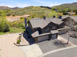 Multi-level residence featuring a brown siding exterior, a dark shingle roof, and multiple chimneys with stone accents