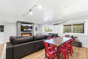 Open-concept living space featuring wood-finish flooring, a contemporary fireplace with a stone surround, and recessed lighting