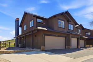 Brown vertical board siding exterior with multiple pitched gables, attached garage, stone accents, and dark trim