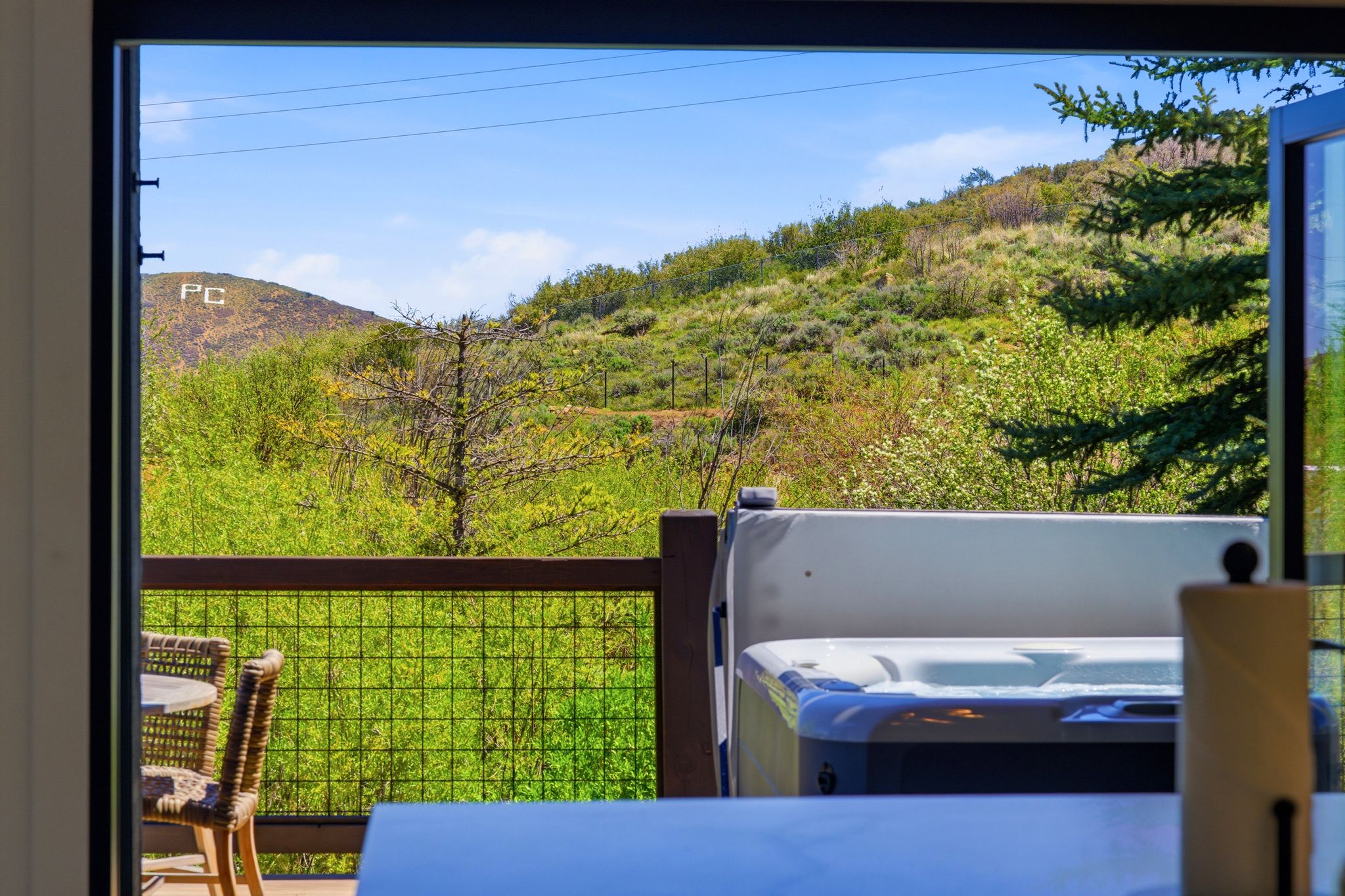 Outdoor deck featuring a built-in hot tub, dark wood railing, and metal grid infill