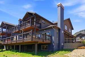 Multi-level decking with wire railing, a tall exterior chimney, and a stone retaining wall