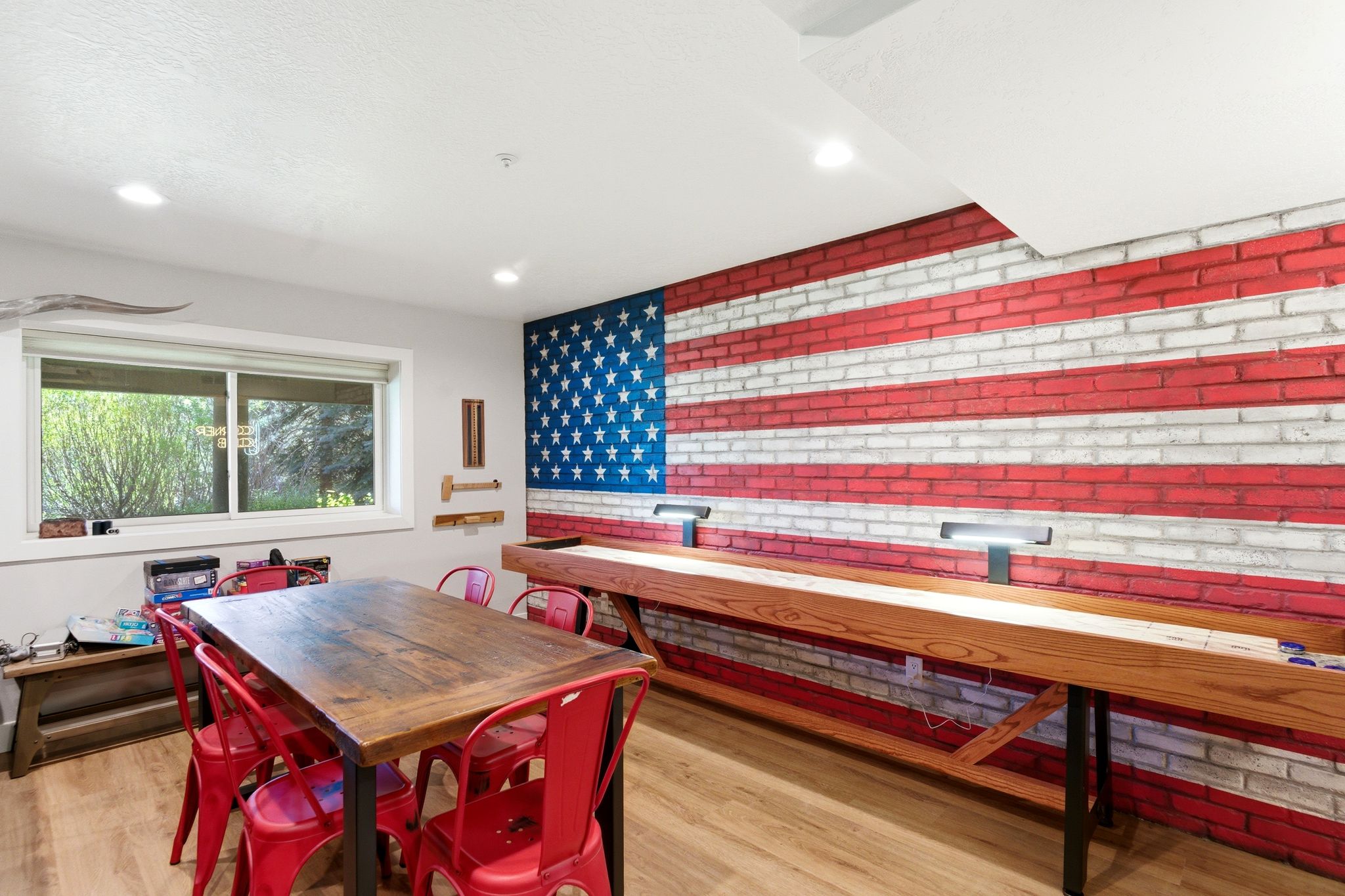 Recreation space featuring a prominent brick accent wall, recessed lighting, wood-finish flooring, and a large window