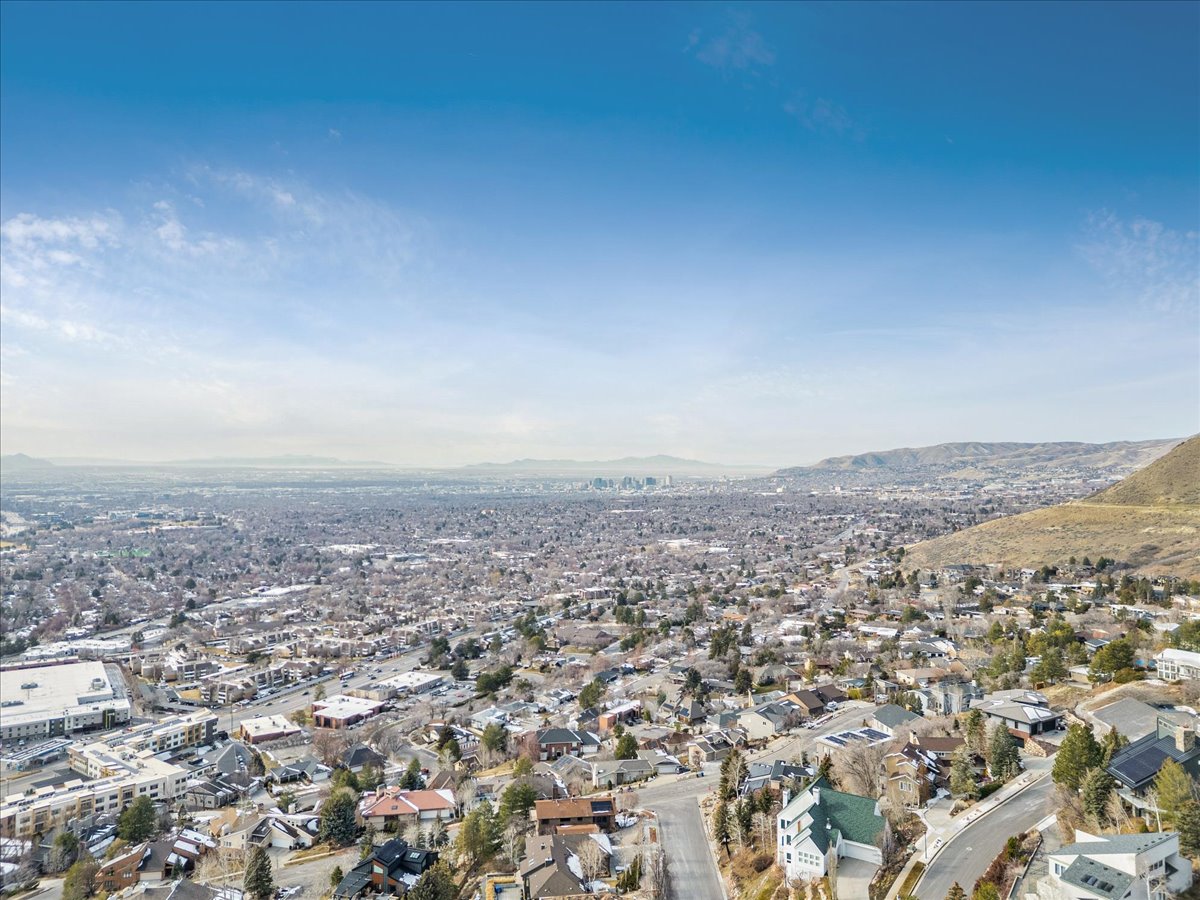 Expansive aerial showcasing a vast urban landscape with distant city skyline and surrounding mountainous terrain