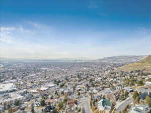 Expansive aerial showcasing a vast urban landscape with distant city skyline and surrounding mountainous terrain