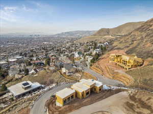 Expansive hillside development featuring multiple properties under construction, a paved winding road, and retaining walls