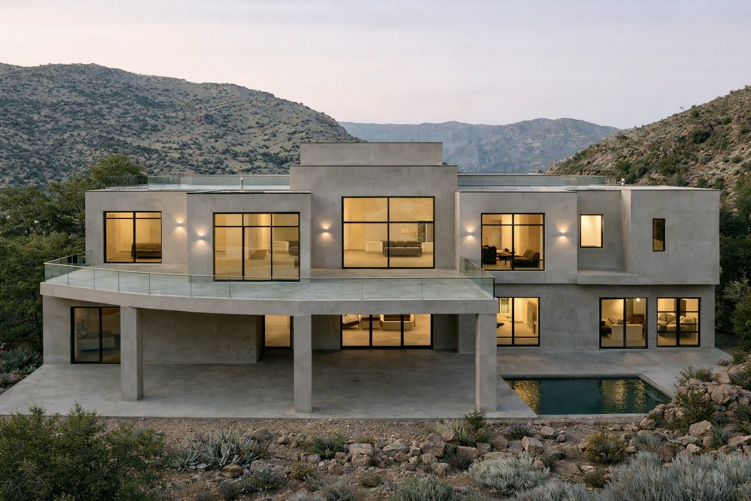 Contemporary stucco exterior featuring a curved balcony with glass railing, an integrated ground-level patio, multiple large windows, and a rectangular plunge pool