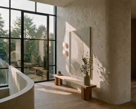 Two-story window wall with dark framing, curved plaster walls, and light wood-finish flooring