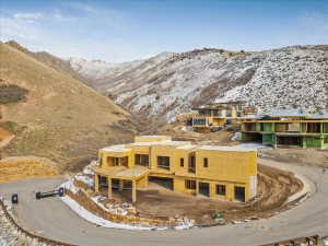 Multi-level construction framing with visible sheathing, featuring a multi-car garage space and a curving driveway