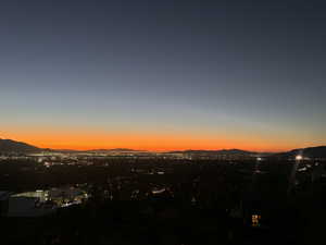 Expansive cityscape with distant mountains under a vibrant orange and blue twilight sky
