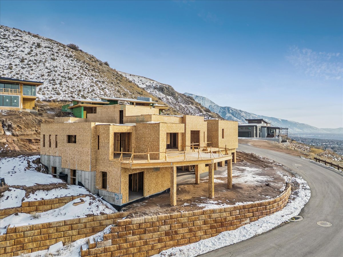 Multi-level construction featuring a prominent deck structure and a stone retaining wall