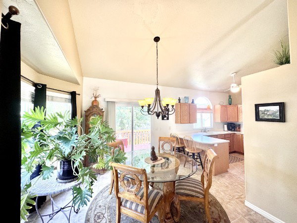 Vaulted ceilings enhance this open-concept dining area, featuring chandelier and bay window