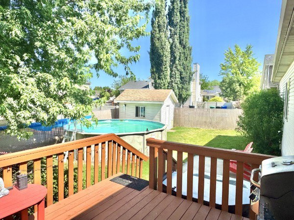 Expansive wood-finish deck with railing overlooking a large backyard