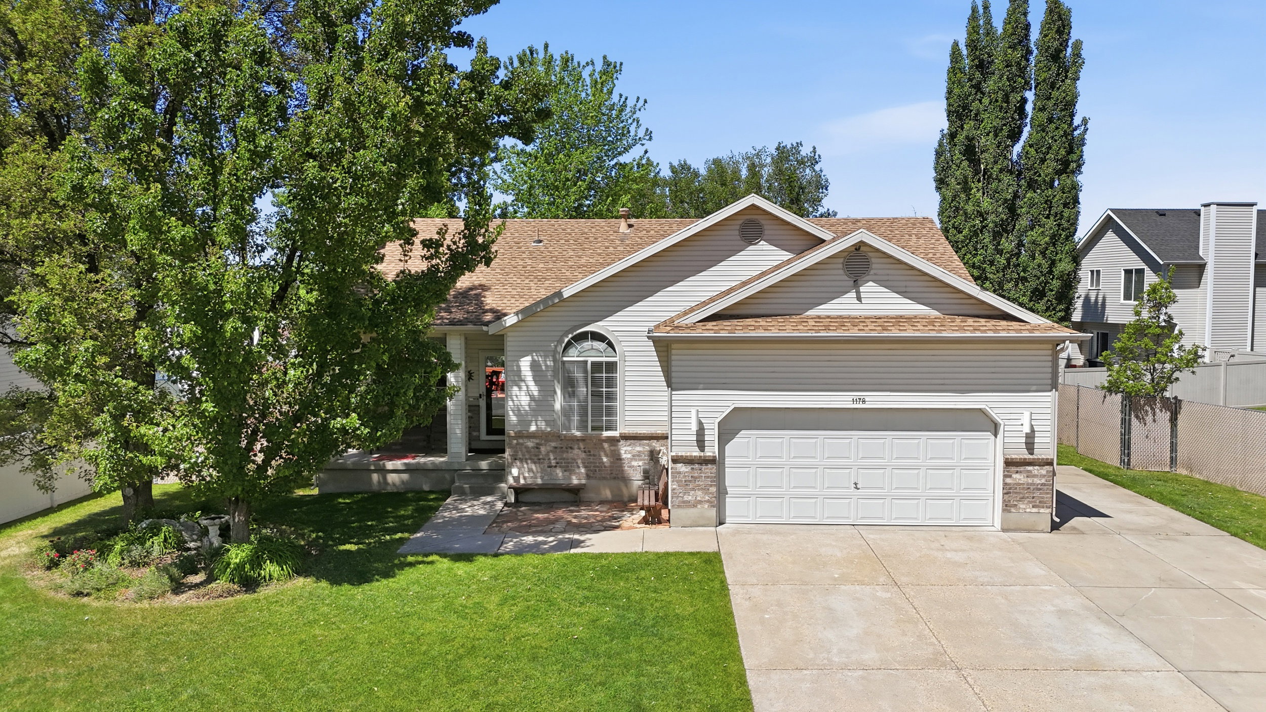 Ranch-style residence featuring a two-car garage, partial stone facade, arched window detailing, and a front porch