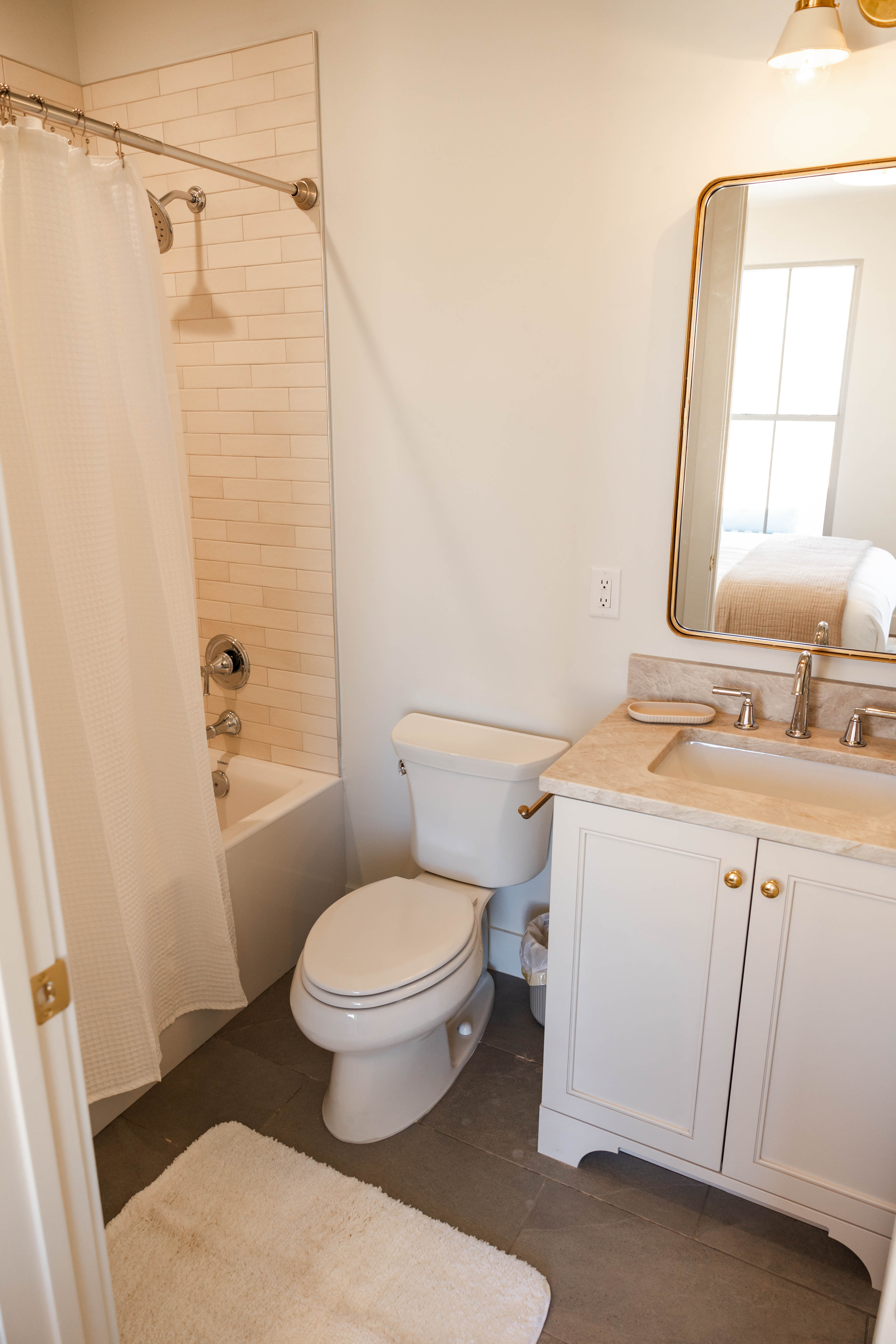 Bathroom featuring a white vanity with gold hardware, a stone-finish countertop, and a rectangular undermount sink