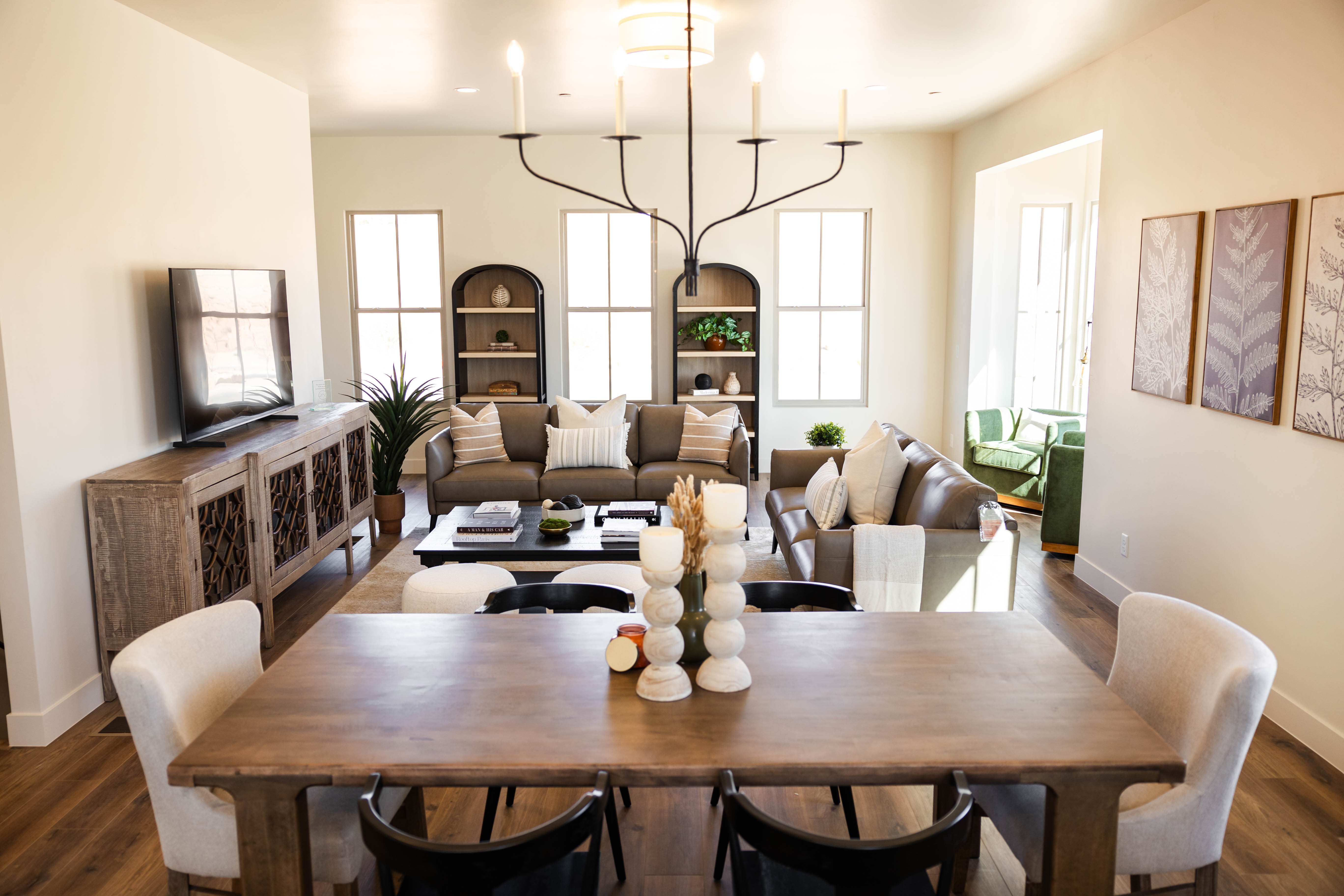 Open-concept dining and living area featuring wood-finish flooring, recessed lighting, and a prominent chandelier