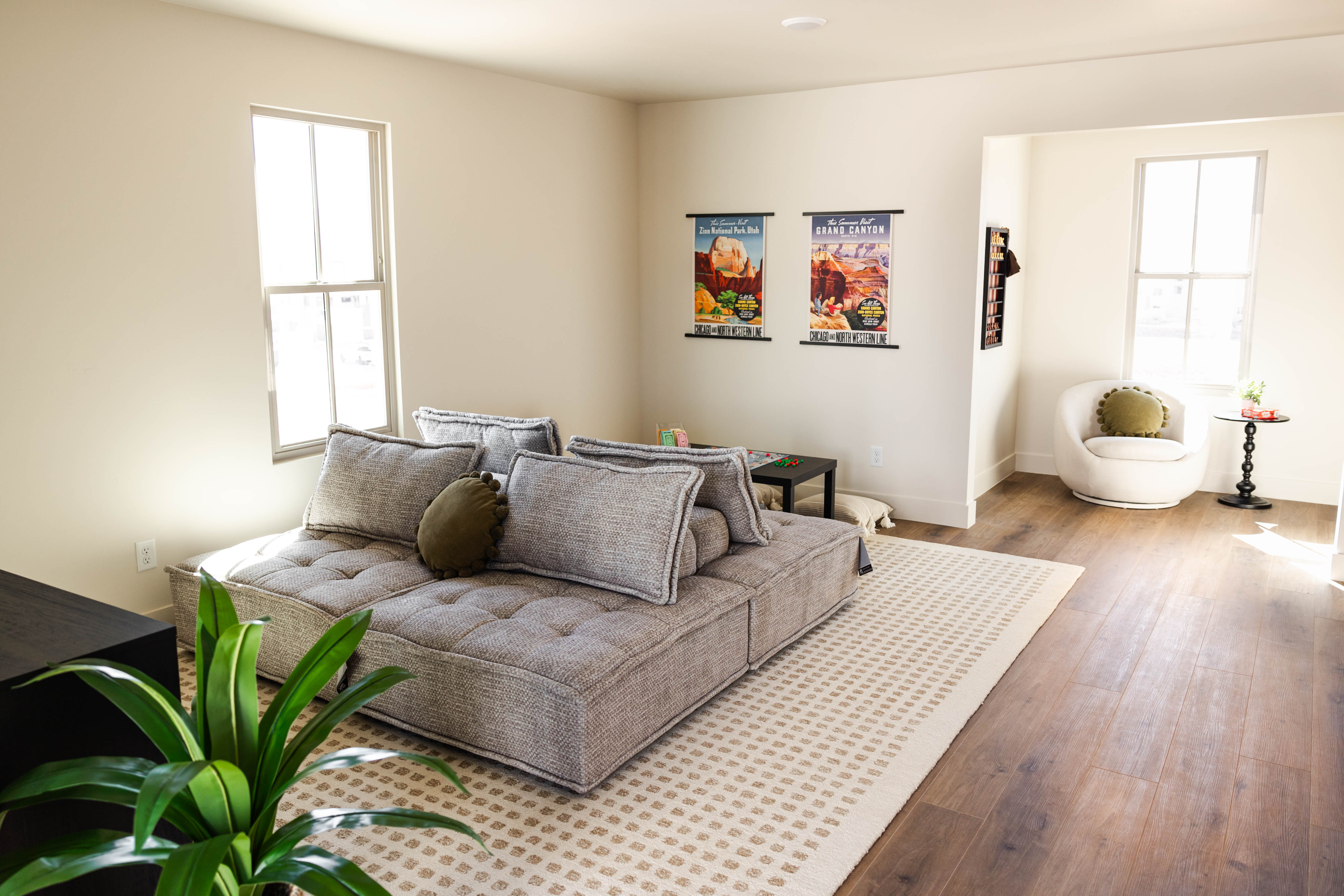 Spacious room featuring light-toned walls, wood-finish flooring, and multiple large windows