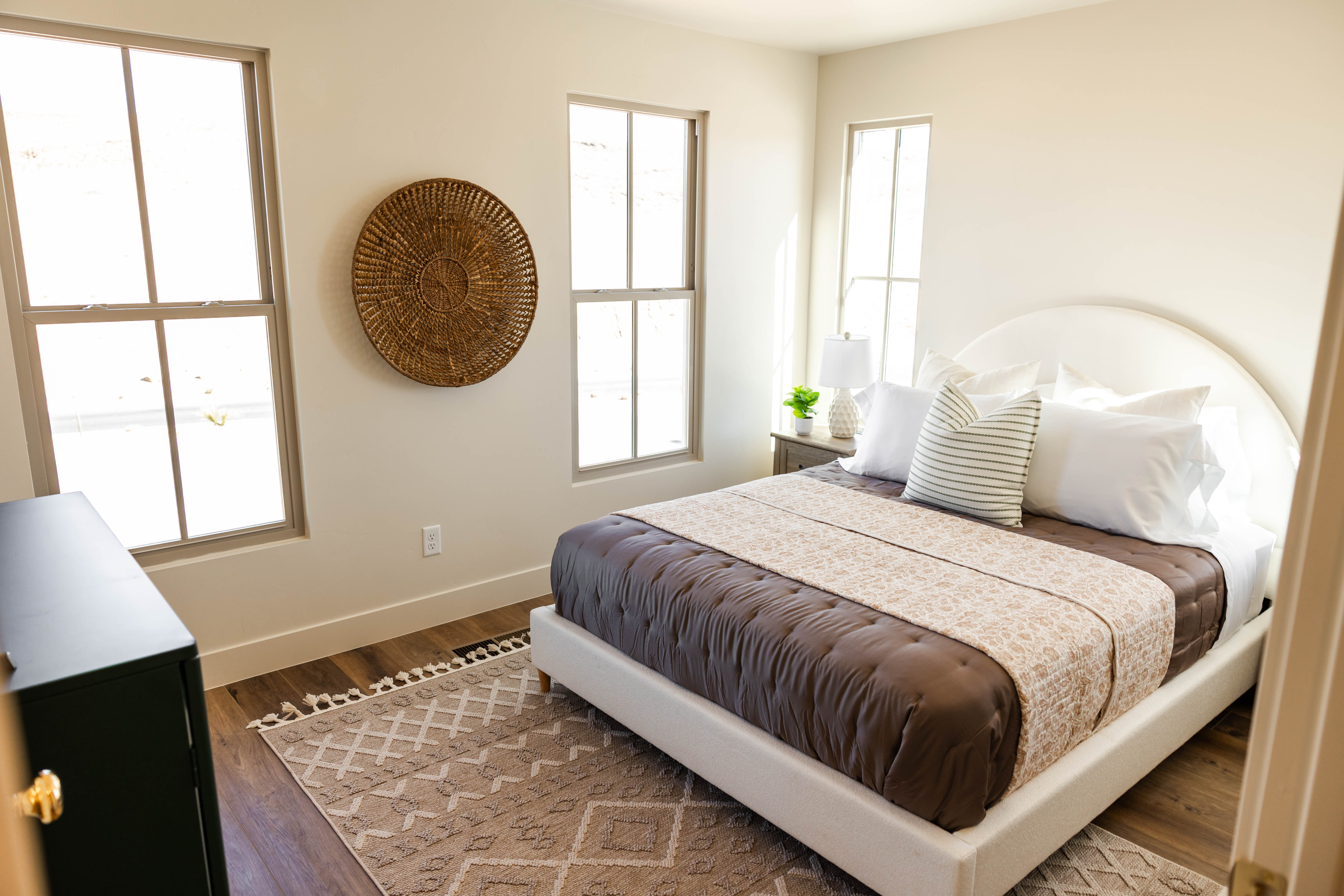Bedroom featuring wood-finish flooring, two large paneled windows, and neutral wall tones