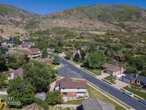 Suburban neighborhood featuring a paved street, mature trees, and a mountainous backdrop