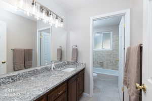 Bathroom featuring a spacious vanity with a granite countertop, undermount sink, and dark wood cabinetry