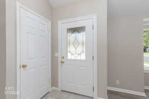 Entryway featuring a white paneled door with decorative glass insert, neutral wall tones, and contrasting flooring materials