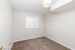 Neutral-toned room featuring light gray walls, white trim, brown carpet, a window with white blinds, and a contemporary ceiling light fixture