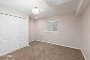 Cozy room featuring neutral-toned walls, plush carpet flooring, and a window with blinds