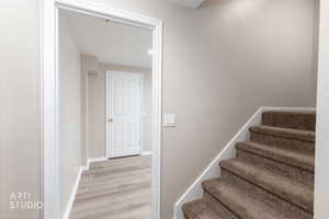 Hallway featuring wood-finish flooring, a six-panel interior door, and light neutral wall paint