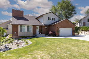 Brick exterior with siding accents, a prominent brick chimney, and a two-car garage