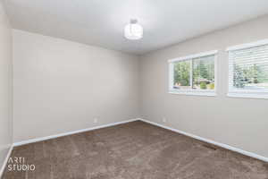 Carpeted room featuring neutral wall tones, white baseboards, and two windows with white blinds