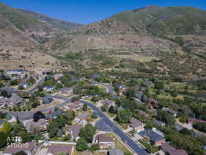 Aerial perspective showcasing a residential community nestled at the base of expansive, tree-covered mountains