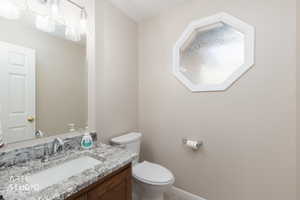 Bathroom featuring a wood vanity with a stone countertop and an undermount sink