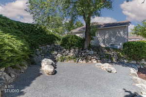 Gravel patio area featuring natural stone landscaping and mature perimeter plantings