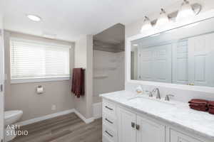 Bathroom featuring a white vanity with a stone-finish countertop, under-mount sink, and brushed nickel hardware