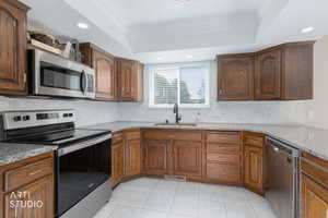 Kitchen featuring wood cabinetry, light-toned countertops, tile flooring, and a hexagonal tile backsplash