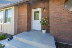 Brick exterior featuring a white entry door with decorative glass, an exterior wall lantern, and a concrete entry pad with steps