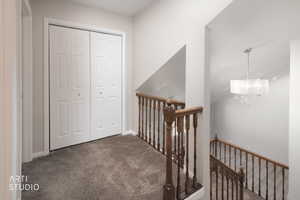 Second-story hallway featuring neutral-toned carpeting and white bi-fold closet doors