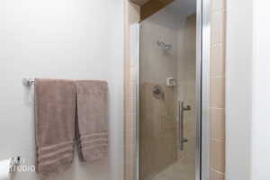 Glass-enclosed shower with neutral-toned tiling and a chrome shower head and fixtures