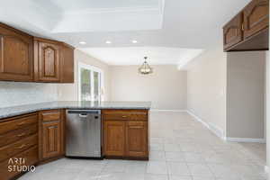 Kitchen featuring wood cabinetry, a stainless steel dishwasher, a hexagonal tile backsplash, and a stone countertop