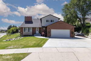 Brick and siding exterior featuring a two-car garage, concrete driveway, and front lawn