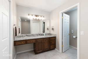 Bathroom vanity featuring a dark wood-finish cabinet with varied storage, a light-toned countertop, and an expansive wall mirror