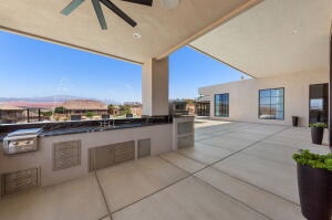 Expansive outdoor patio featuring an integrated outdoor kitchen with grill, a ceiling fan, and a large open-air section