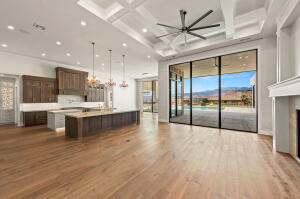Expansive interior with wood-finish flooring, a coffered ceiling with recessed lighting, and a large ceiling fan