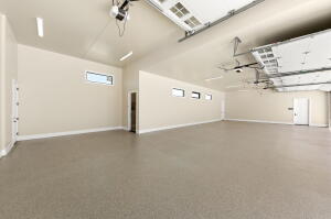 Spacious garage with high ceilings, light beige walls, and light gray concrete flooring