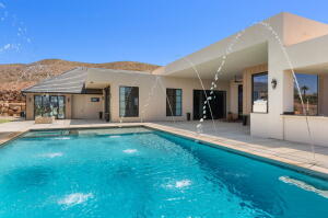 Contemporary stucco exterior featuring an expansive swimming pool with water features and integrated patio space