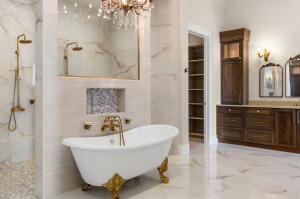 Freestanding clawfoot tub with gold-tone fixtures, complemented by a walk-in shower featuring matching hardware