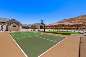 Multi-sport court with a basketball hoop, green turf area, and surrounding desert landscaping