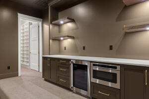 Built-in cabinetry with a light-toned countertop, stainless steel appliances, and illuminated floating shelves