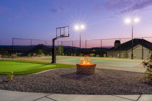Outdoor sports court featuring a basketball hoop, perimeter fencing, and dedicated lighting