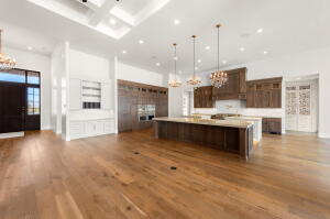 Spacious open-concept kitchen and living area featuring wood-finish flooring, a coffered ceiling, and recessed lighting